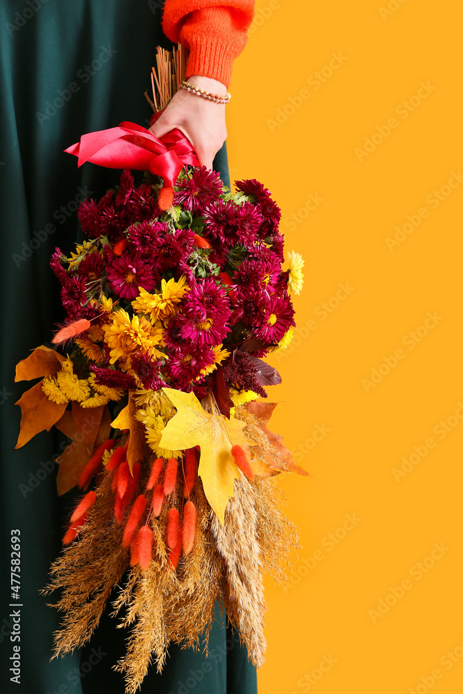 女人拿着美丽的秋季花束，背景是彩色，特写