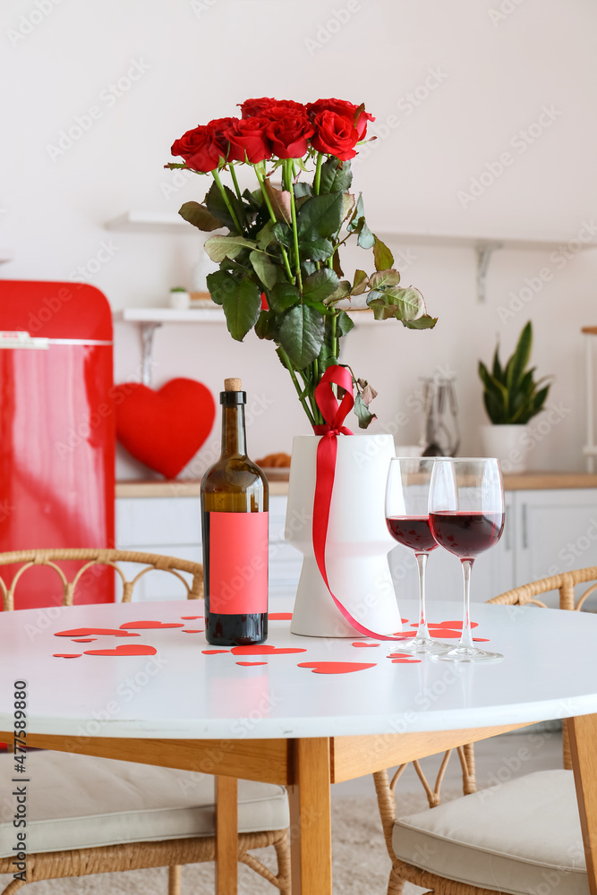 情人节餐桌上摆着一瓶葡萄酒、玻璃杯和鲜花