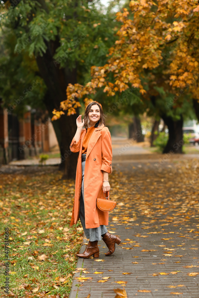 秋天的城市街道上，带着时尚手提包的快乐年轻女人