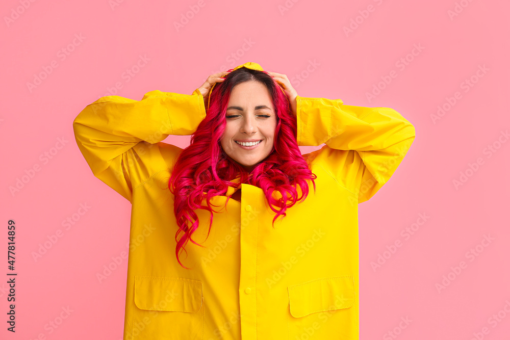 美丽的女人，明亮的头发，穿着彩色背景的雨衣