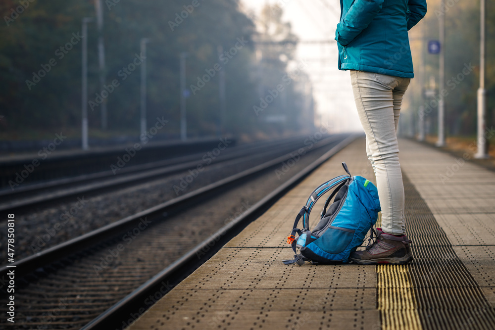 独自一人在空荡荡的火车站等火车。背着背包的女人站在火车站