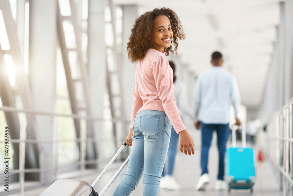 Happy black girl looking back walking in airport