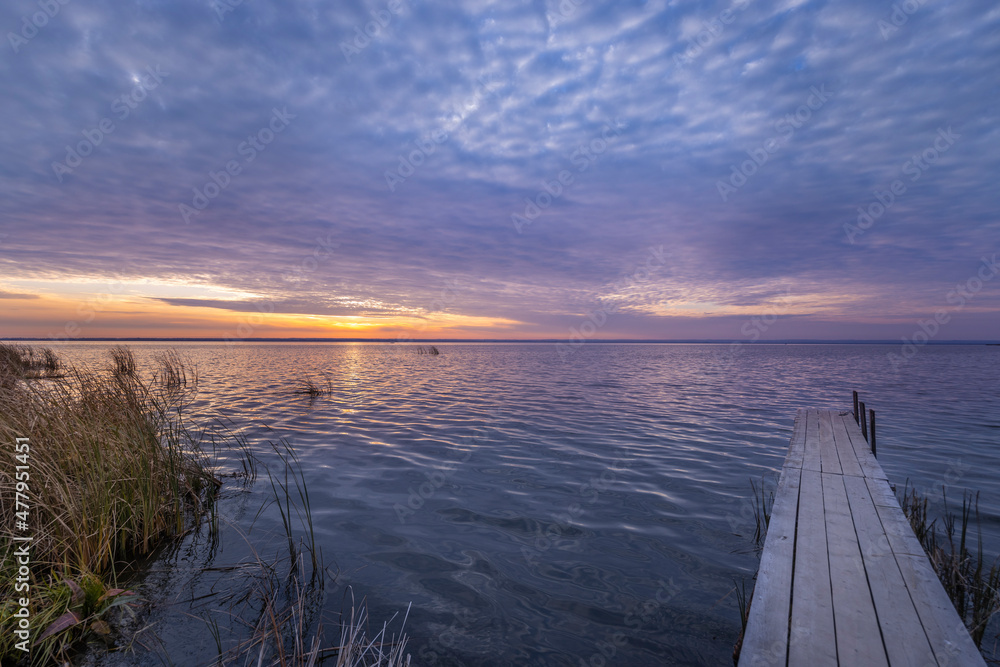 带木码头的秋季湖岸上五彩缤纷的日出。带湖的秋季景观