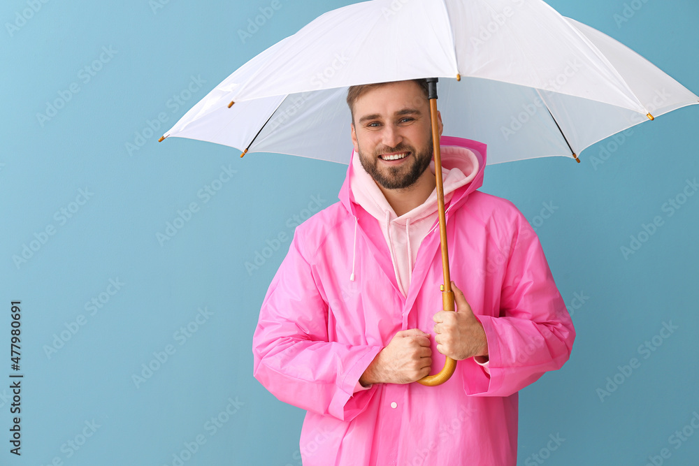 穿着时尚雨衣，彩色背景下带着雨伞的年轻人