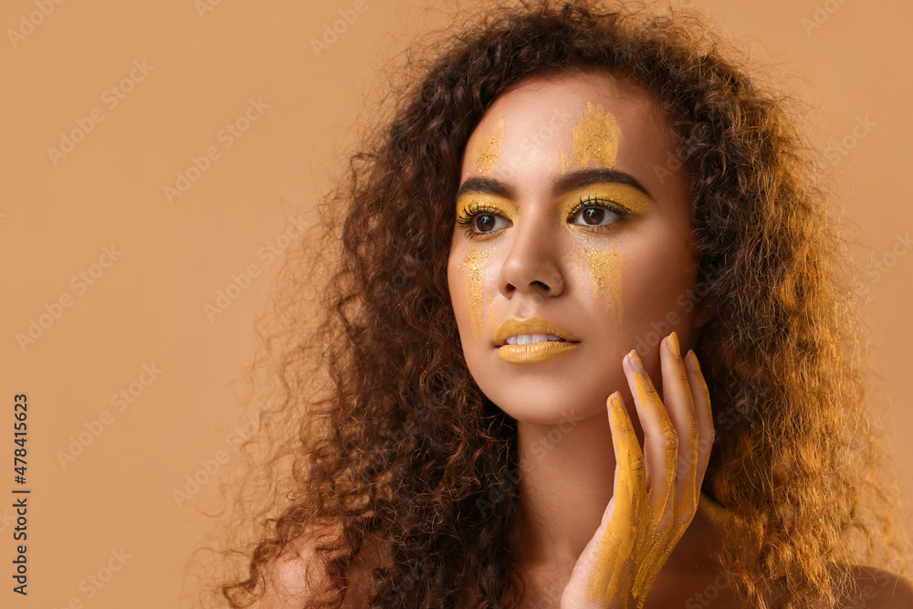 美丽的年轻女子，脸上和身上都涂着黄色的颜料，背景是彩色的