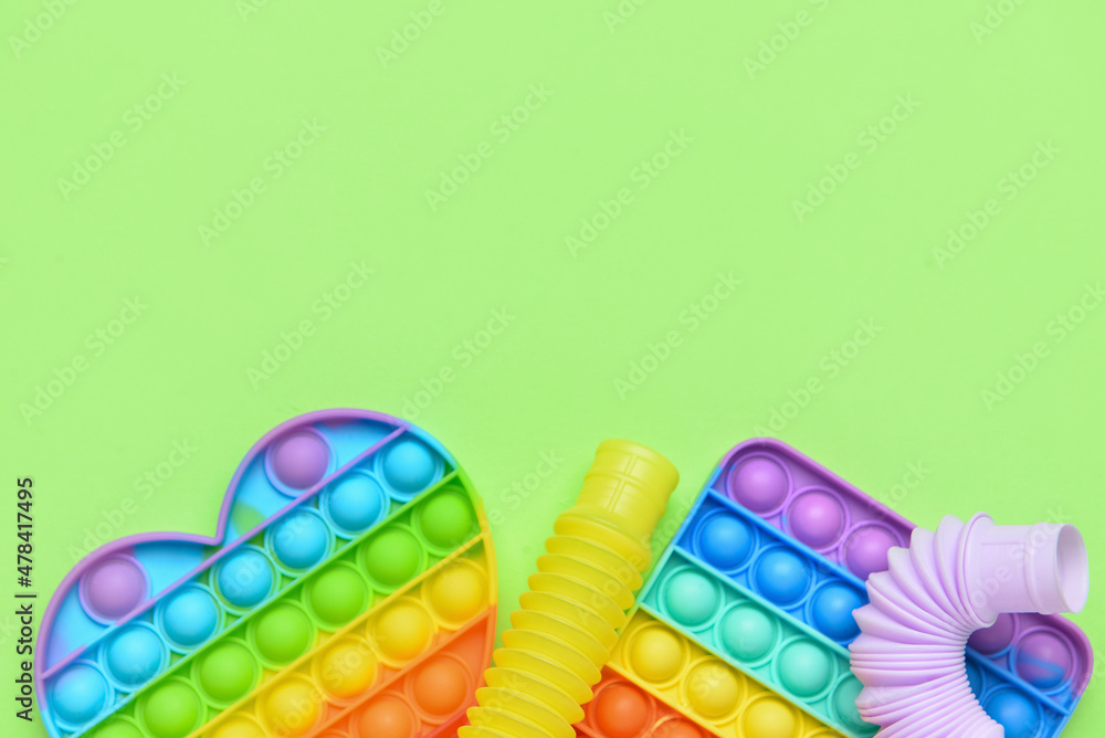 彩色流行管和绿色背景的Pop-it fidget玩具