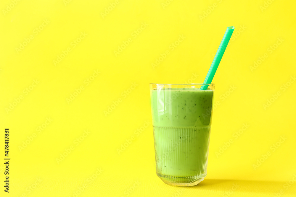 一杯黄色背景上有吸管的绿色果汁