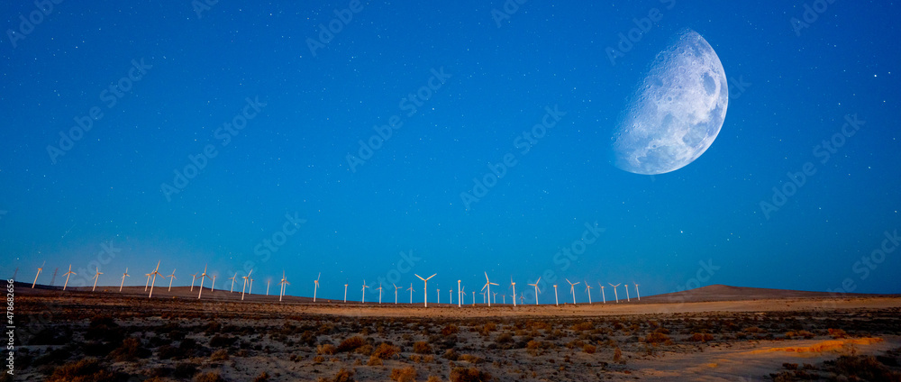 Wind generators in the night desert and the moon in the sky