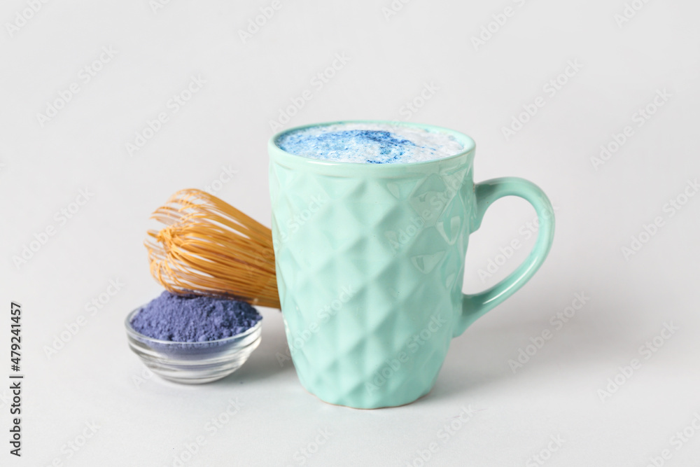 一杯蓝色抹茶拿铁，碗里有粉末，白色背景上有追逐