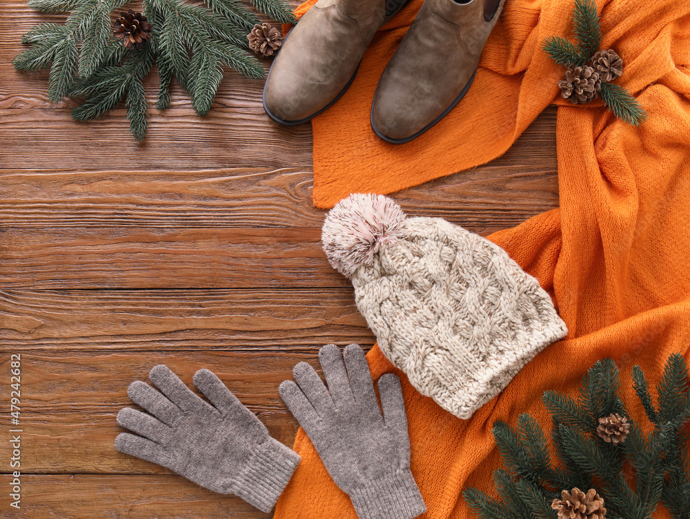 Warm clothes, shoes and fir tree branches on wooden background