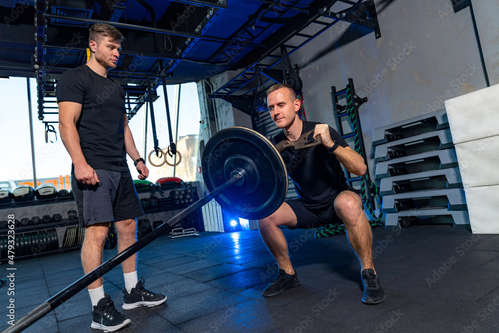 强壮的男子在健身房刻苦训练。两名肌肉发达的运动员正在努力训练。