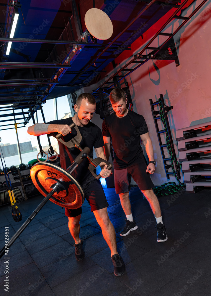 两名肌肉无力的运动员努力训练。强壮的男子在健身房里努力训练。