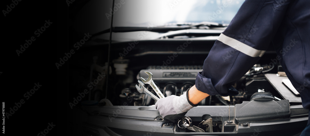 汽车修理工用扳手的手。汽车修理厂。修理工在修理汽车的发动机。