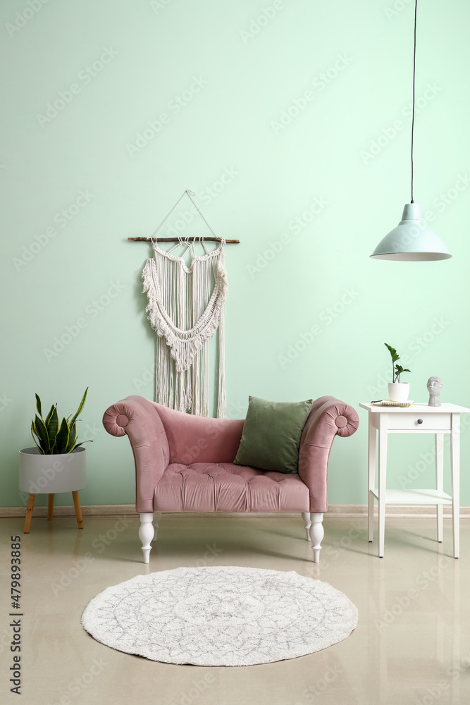 粉色扶手椅和桌子，绿色墙壁附近有室内植物