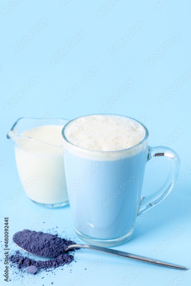 一杯美味的蓝色抹茶拿铁，彩色背景的粉末和牛奶
