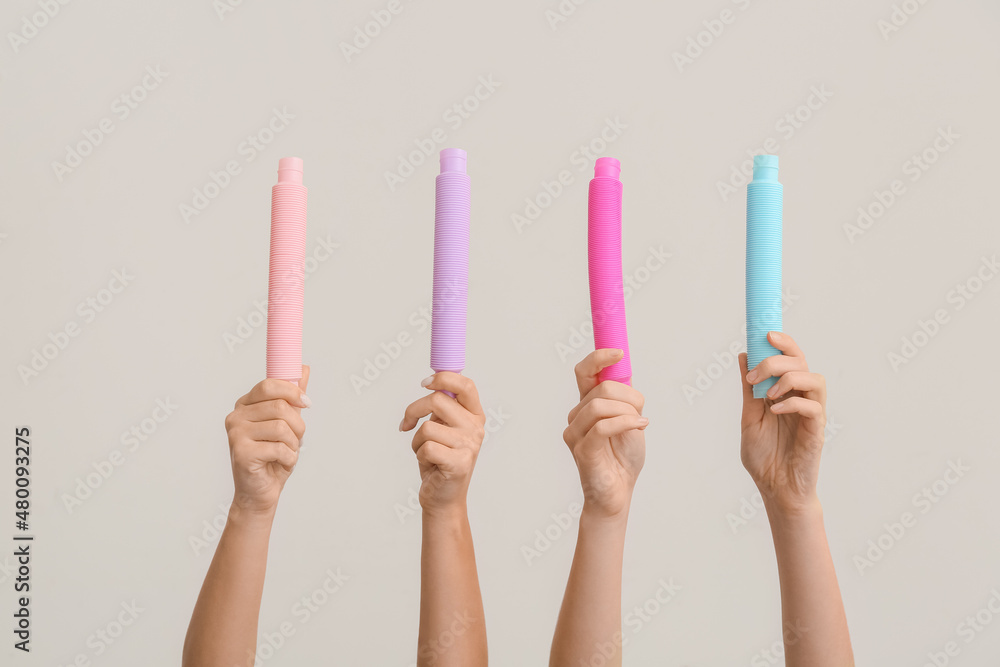 Hands with popular pop tubes on light background