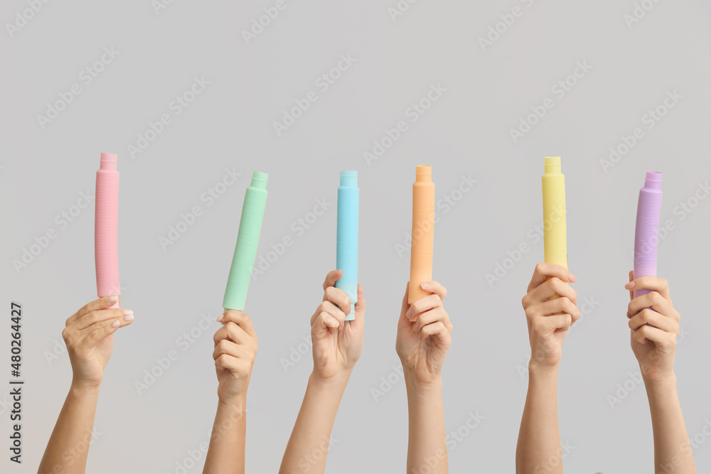 Hands with popular pop tubes on light background