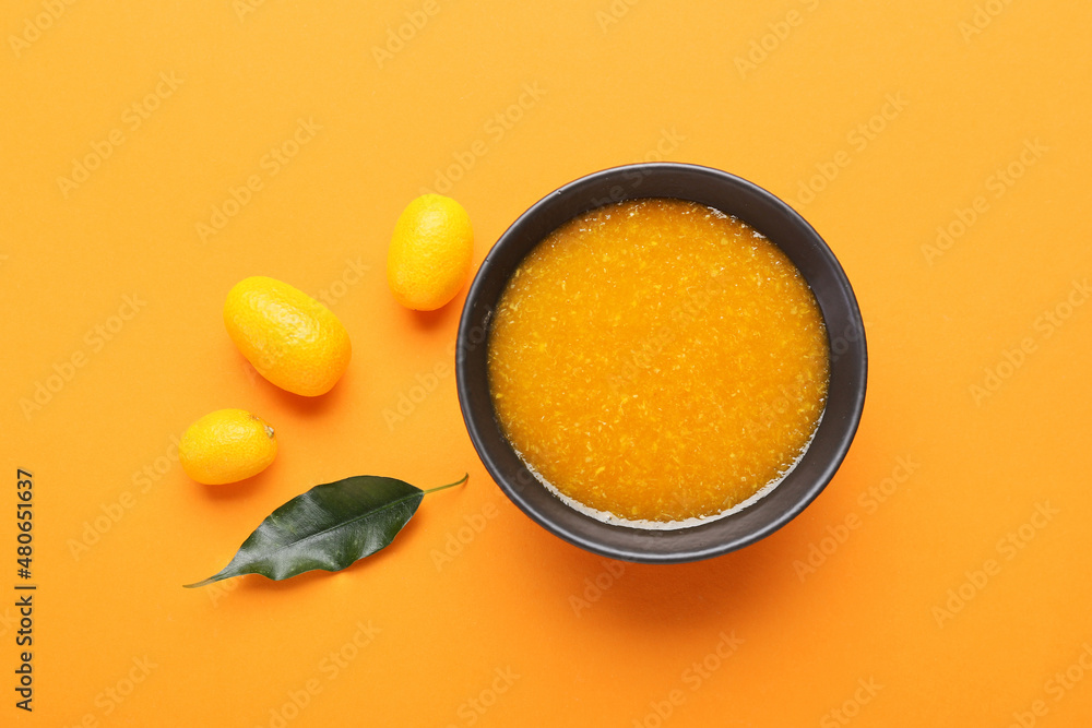 一碗美味的金桔酱和橙色背景的新鲜水果