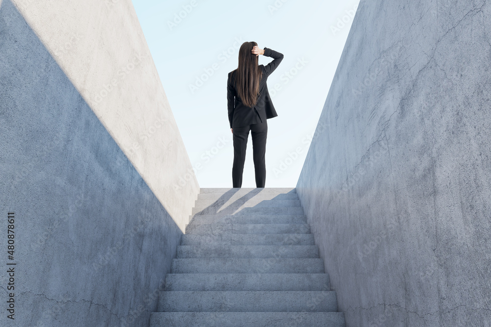 深思熟虑的女商人站在抽象的混凝土楼梯上与苏一起走向成功的背影