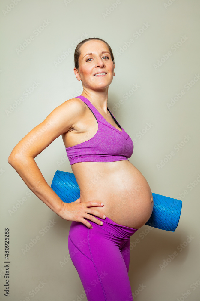 大肚子孕妇抱着瑜伽伴侣