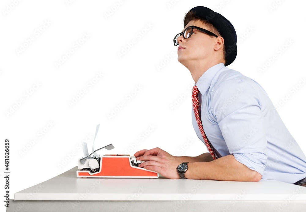 戴眼镜的年轻滑稽男子在旧打字机上写字