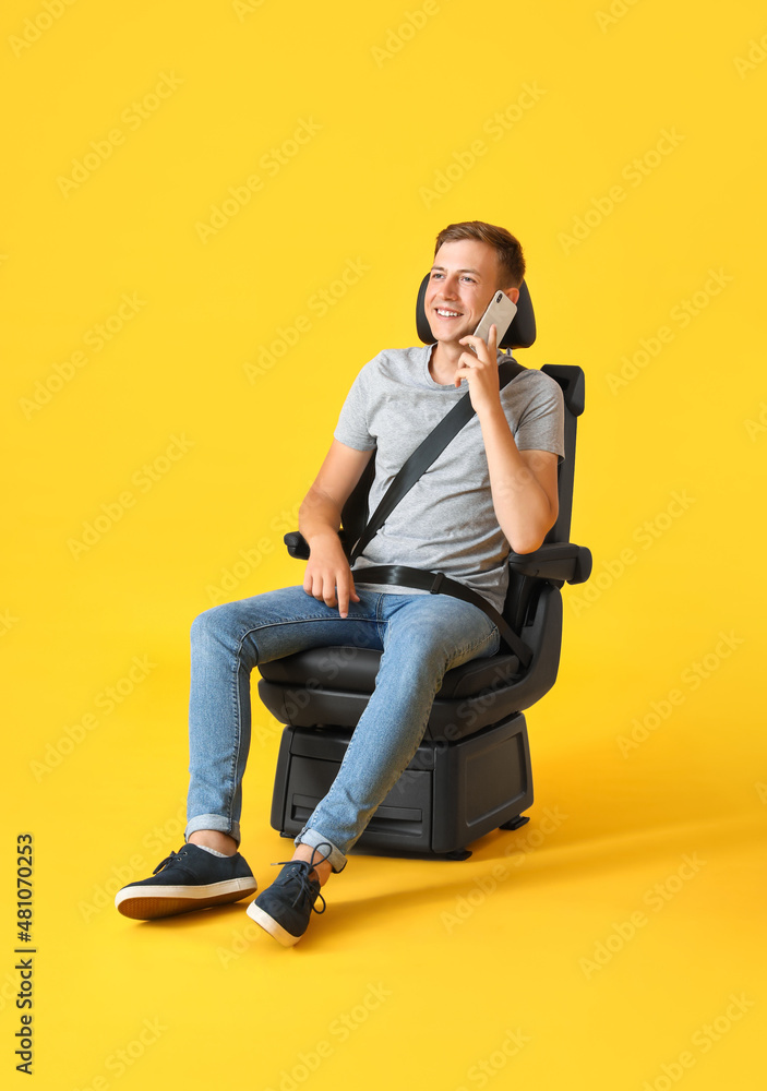 Man in car seat talking by phone on color background