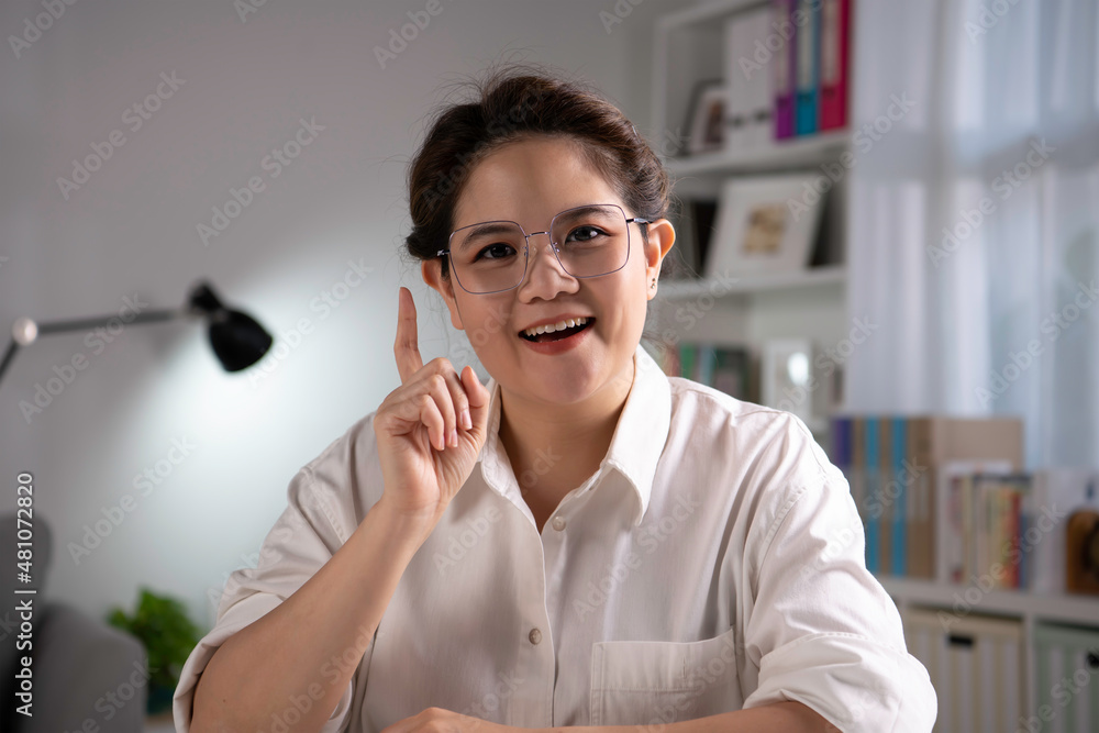 Portrait shot of happy friendly and confident Asian businesswoman sitting on a couch at home, lookin
