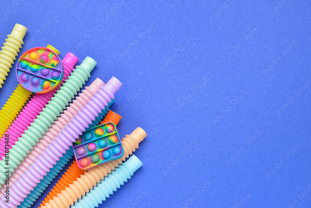 蓝色背景下的彩色Pop Tubes和Pop-it坐立不安的玩具
