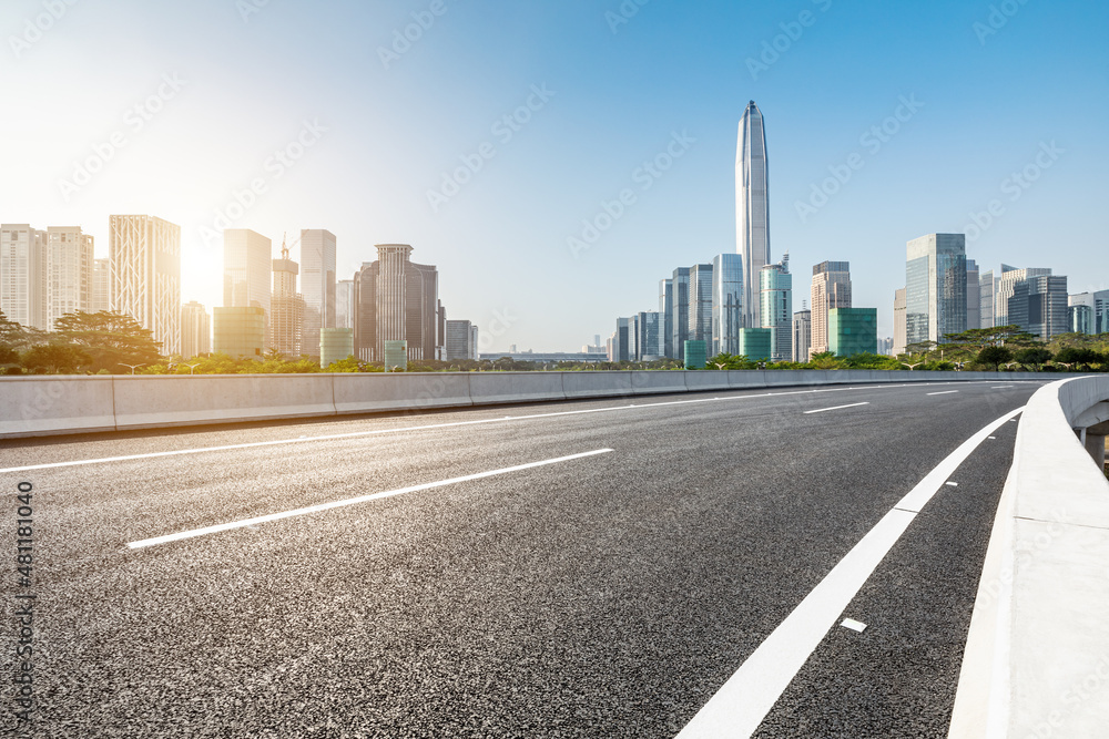Asphalt road and city skyline with modern commercial office buildings in Shenzhen at sunrise, China.