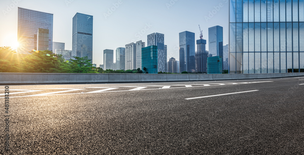 日出时，中国深圳的沥青道路和城市天际线，以及现代化的商业办公楼。