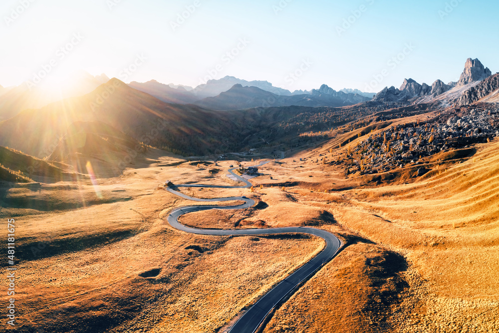 Fantastic aerial view on winding road in autumn mountain valley at sunset. The golden sunset light i