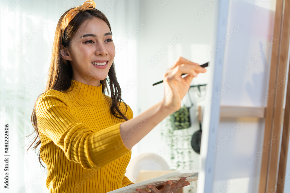 亚洲年轻才女艺术家在家里的画板上上色。
