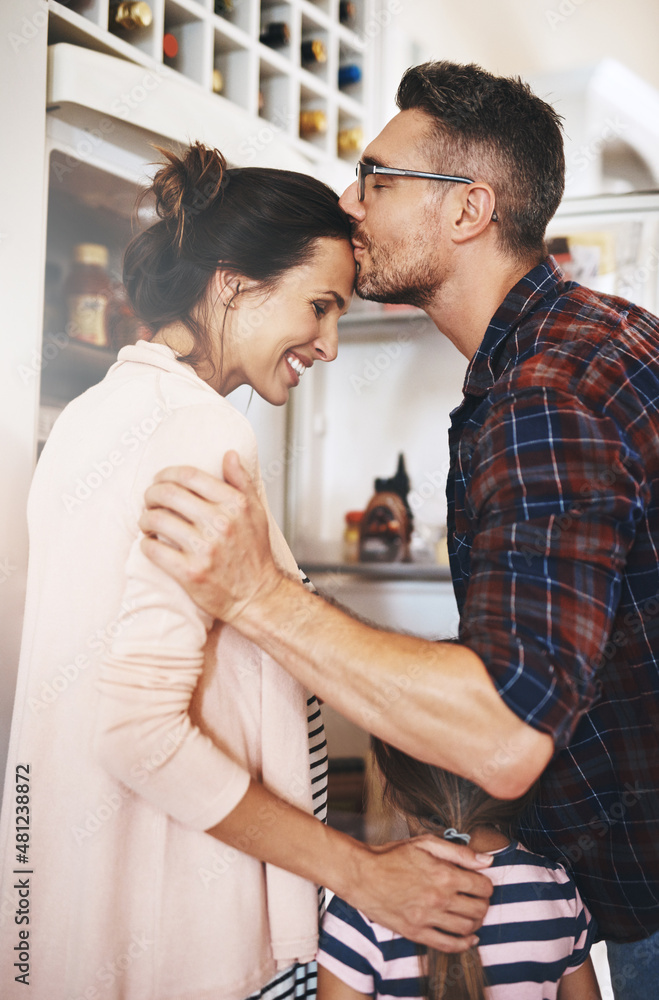 他很欣赏她。一张丈夫和家人在厨房里深情亲吻妻子的照片。