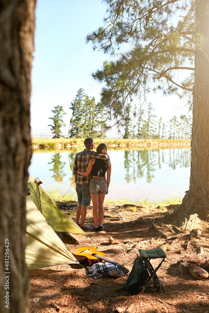 Into the woods. Shot of a young couple camping by a lake.