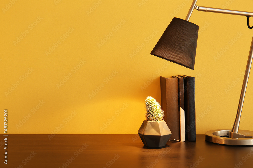 彩色墙附近桌子上的发光灯、室内植物和一叠书