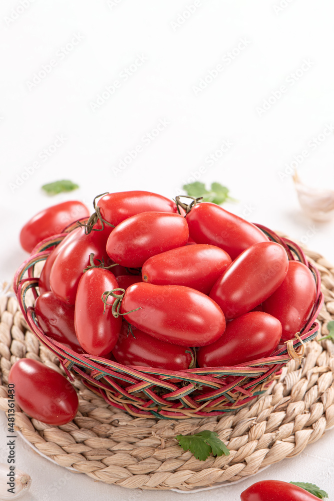 Fresh cherry tomatoes in a basket with spices.