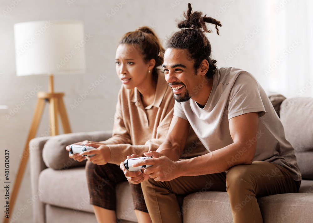 一对非洲裔美国夫妇一起用电子游戏机笑着玩电子游戏