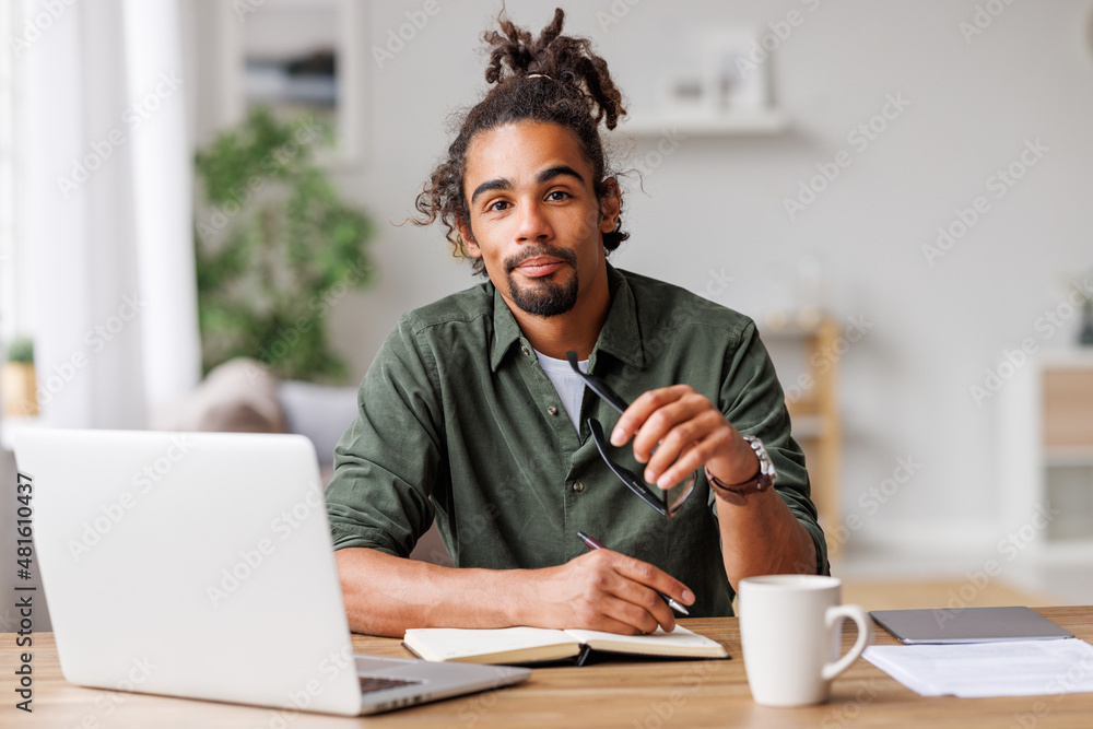 年轻的非洲裔美国男子自由职业者，在笔记本电脑上远程工作或在家在线学习