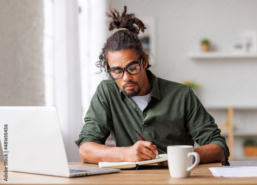 在笔记本电脑上远程工作或在家在线学习的年轻非裔美国男子自由职业者