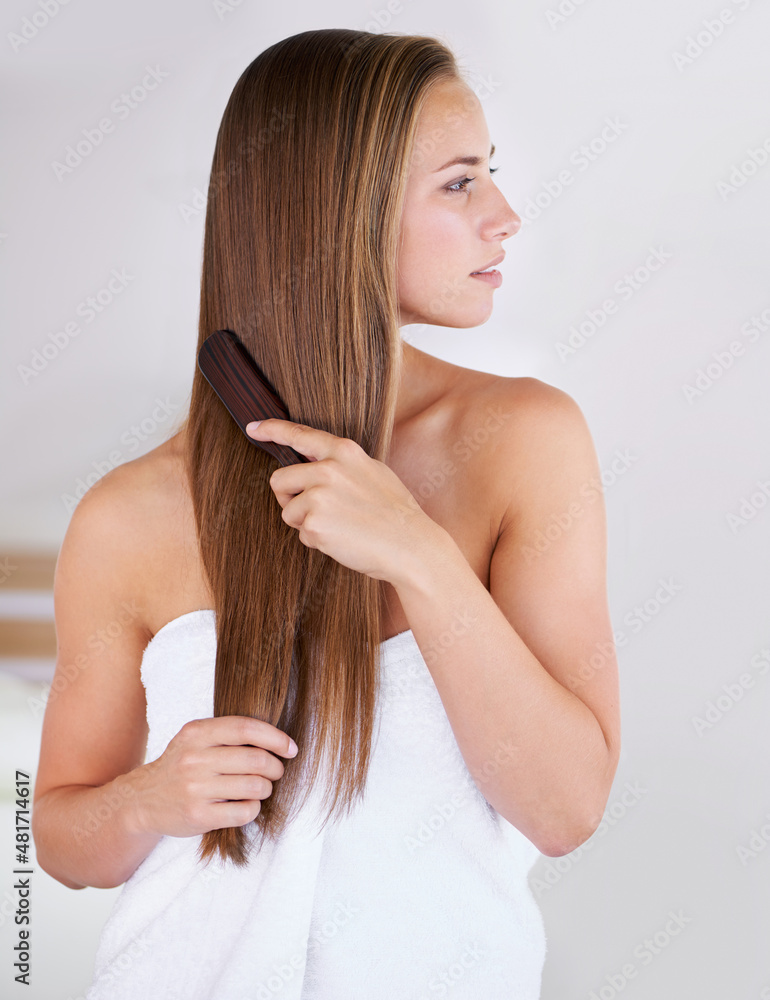摆脱多余的缠结。一个漂亮的深色女人梳着她健康的长发。