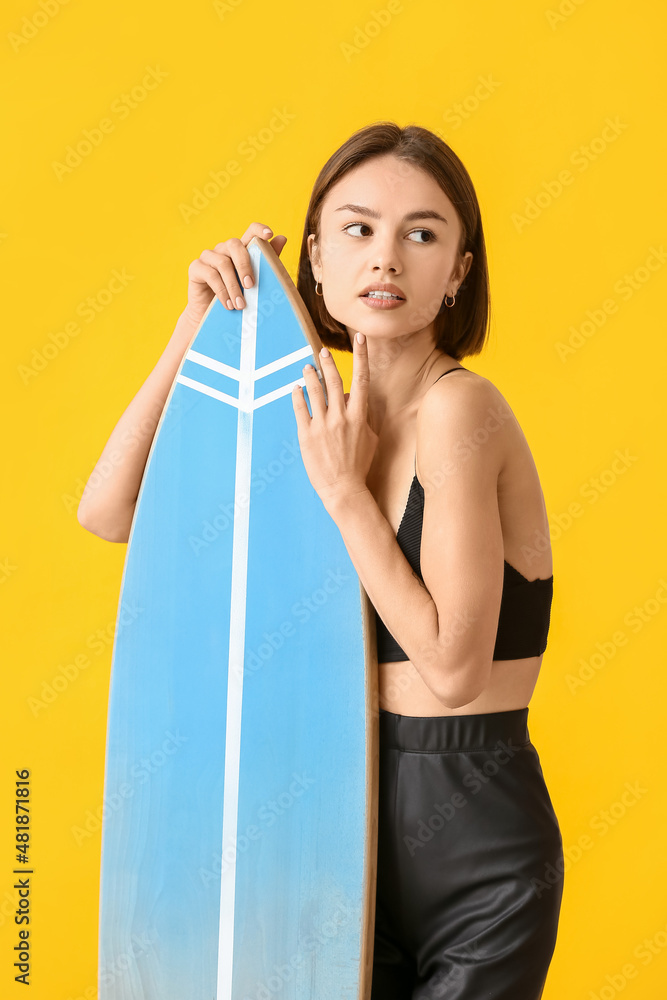 美丽的年轻女子，彩色背景上有冲浪板