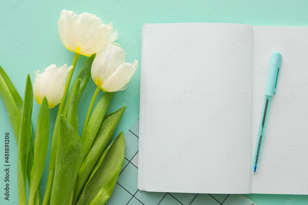 Open notebook, pen and tulips on color background, closeup