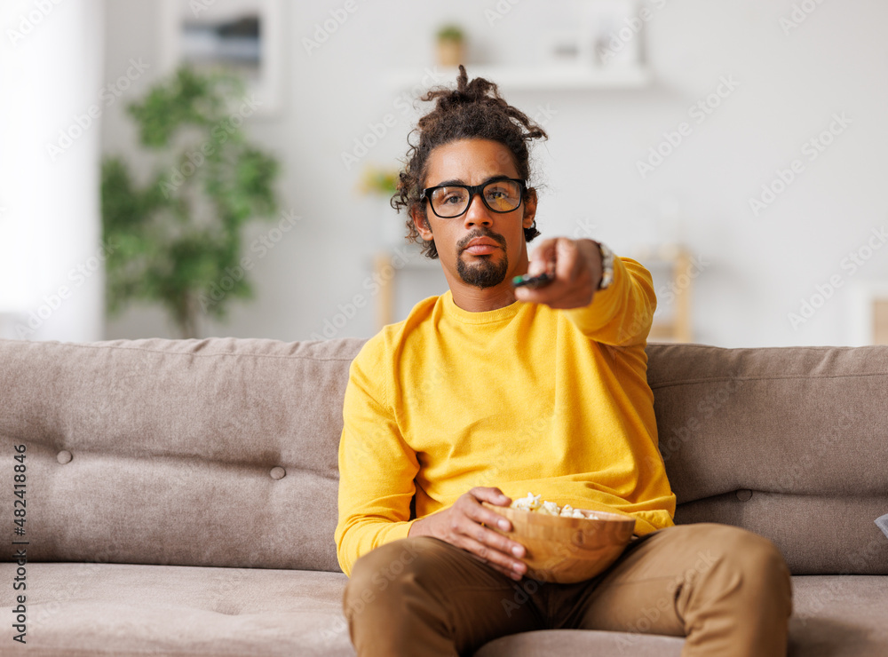 无聊疲惫的非裔美国人在家放松时用遥控器换电视频道