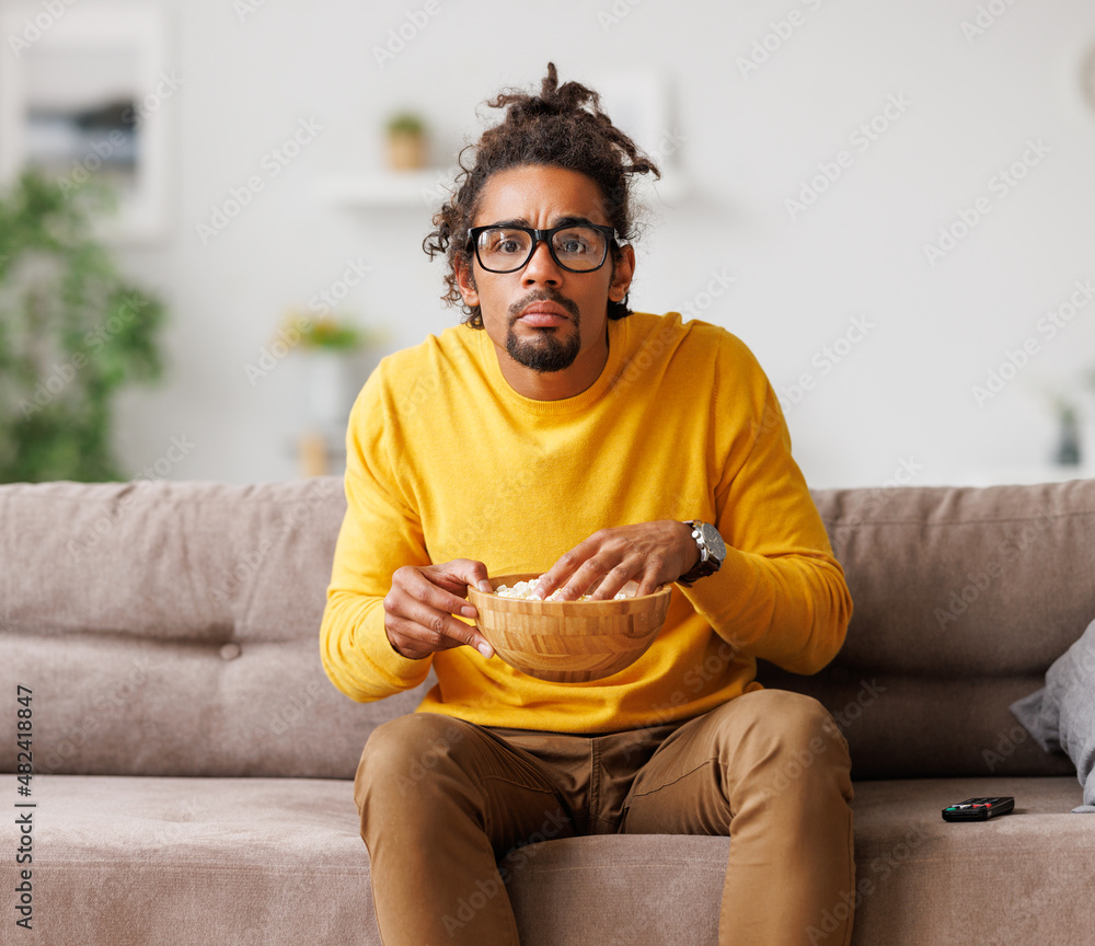 无聊疲惫的非裔美国人在家放松时用遥控器看电视