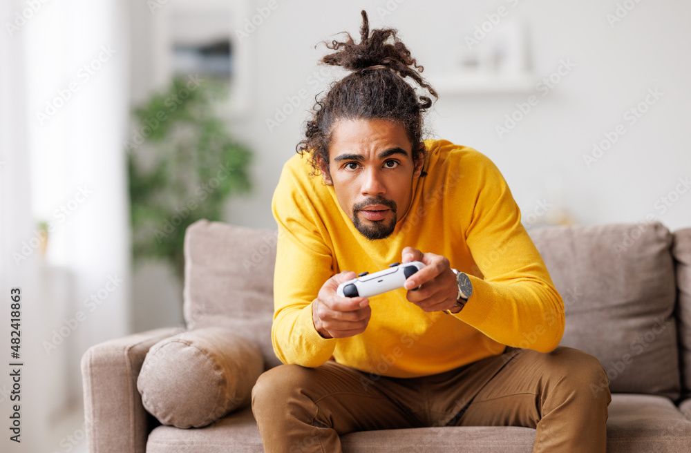 年轻乐观快乐的非裔美国人，带着无线游戏板在家玩电子游戏