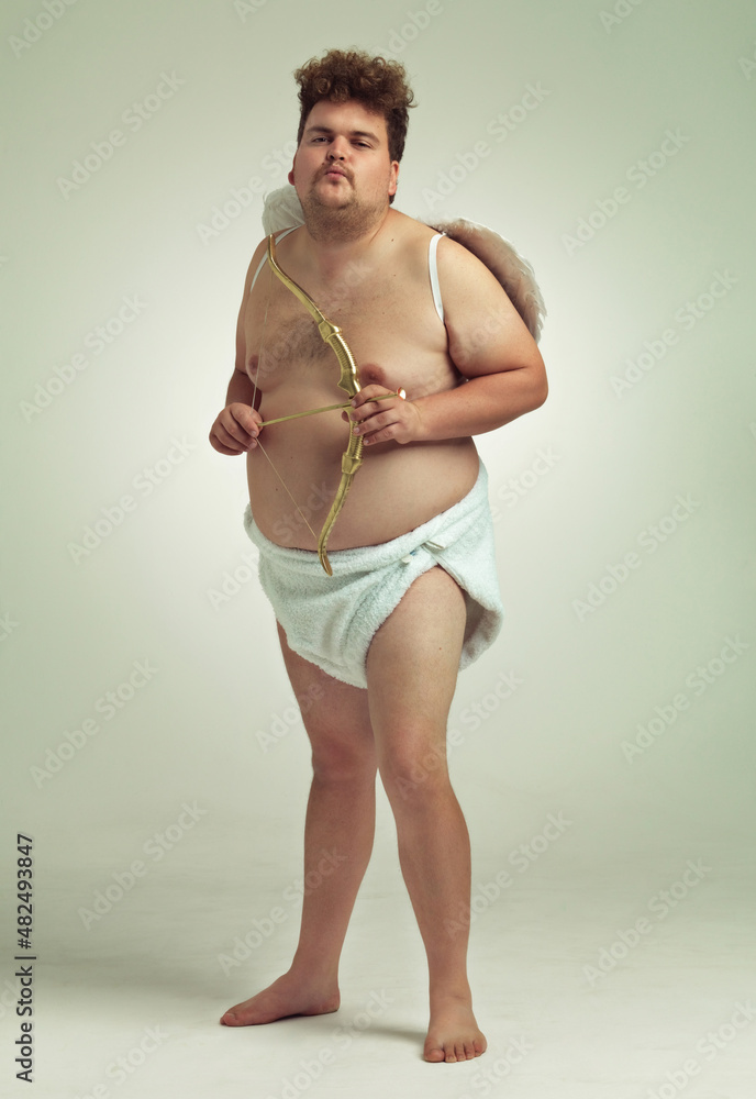 瞄准你。一个肥胖的男人打扮成一个带弓箭的小天使。