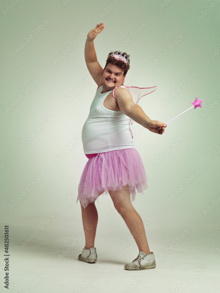 魔杖很有趣。一个超重的男人滑稽地穿着粉色仙女服装。