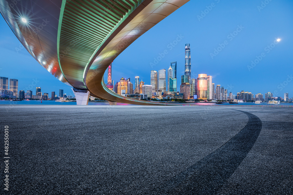 中国，夜晚的上海，空旷的柏油路和现代商业建筑的城市天际线。