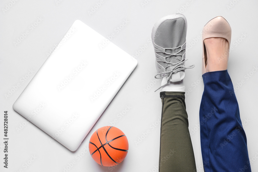 穿着运动鞋和高跟鞋的女人的腿，背景是笔记本电脑和球