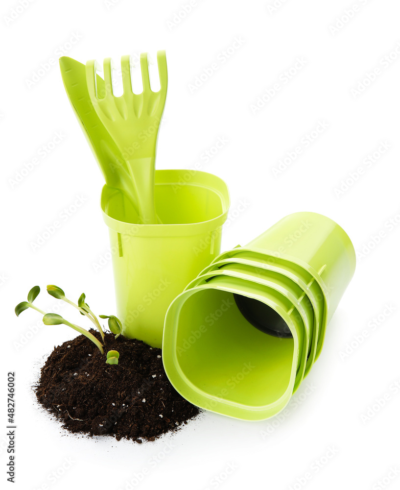 Soil with seedlings, flower pots and gardening tools on white background